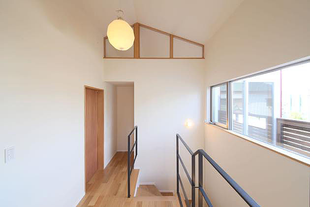 ウッドテラスに面した天井が高く明るい階段ホール,木製建具の素材感が印象的な階段ホール１
