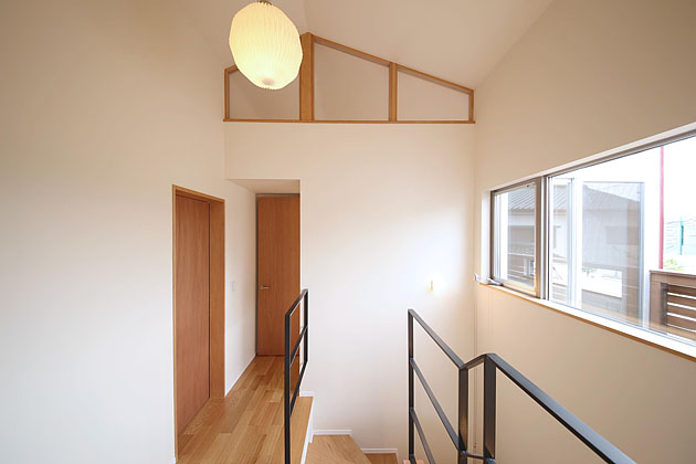 ウッドテラスに面した天井が高く明るい階段ホール,木製建具の素材感が印象的な階段ホール４